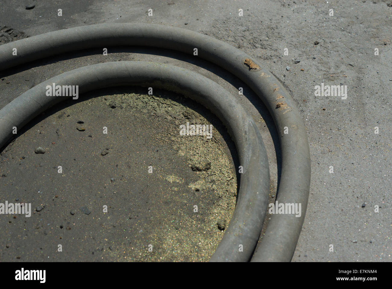 A high pressure hose lying on the ground acts as a catch for chalcopyrite rich copper concentrate. Stock Photo