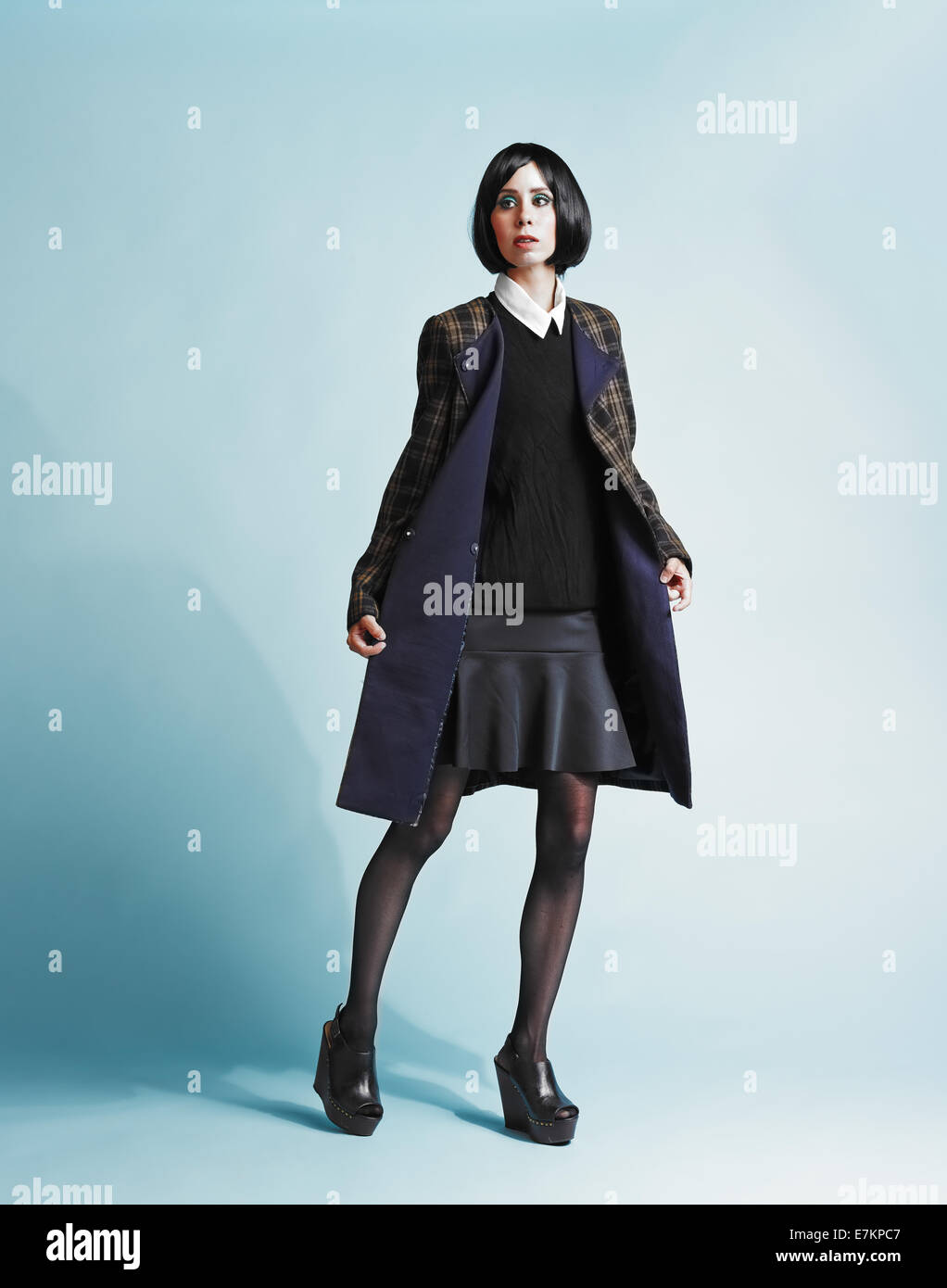 Full length portrait of beautiful young woman wearing an overcoat - studio shot Stock Photo