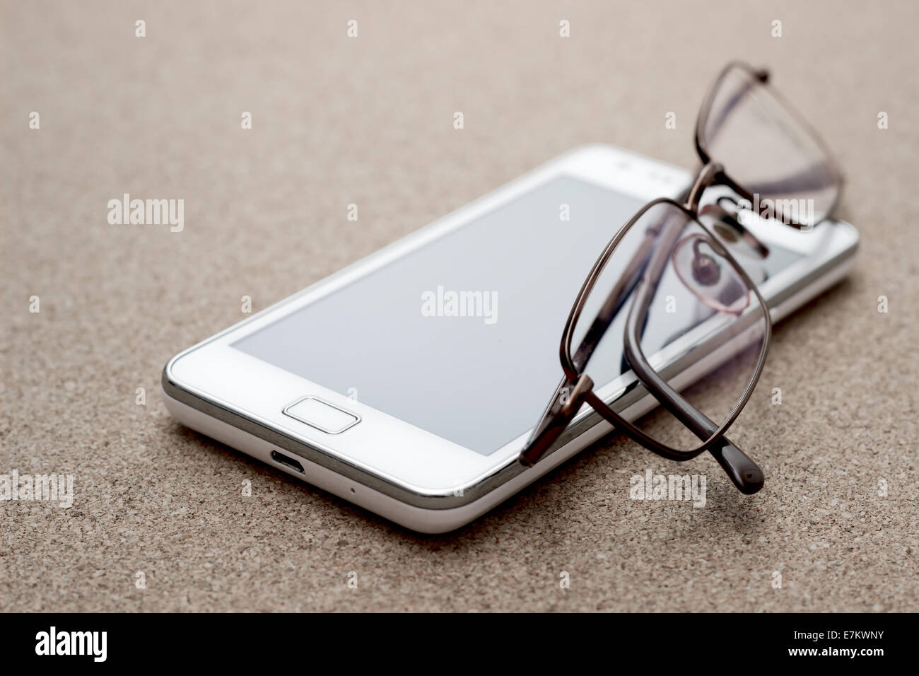 cell phone and glasses on corck board, close up Stock Photo