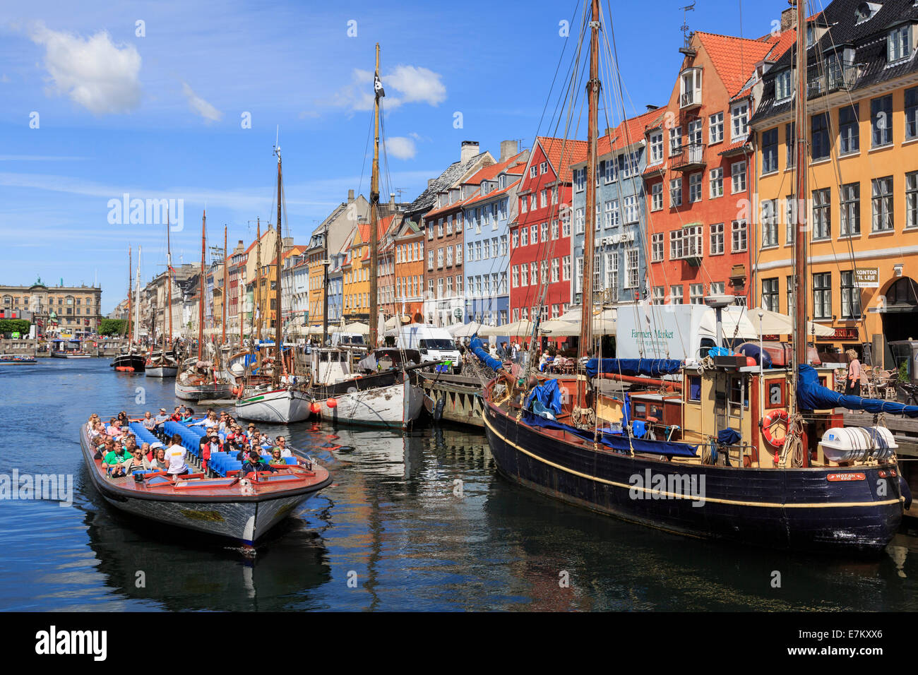 Tourists on Copenhagen canal tour boat with old boats moored in front of colourful buildings. Nyhavn Copenhagen Zealand Denmark Scandinavia Stock Photo