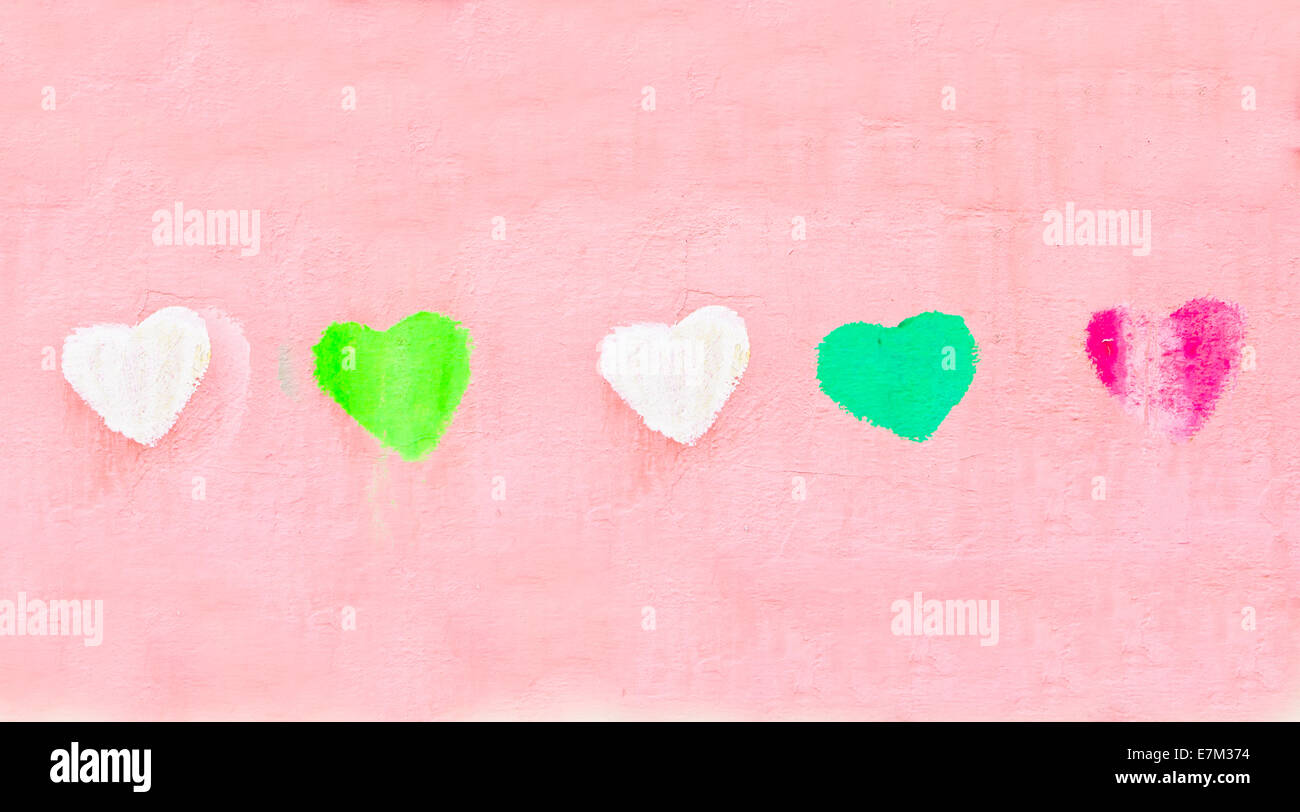 Row of colorful painted heart shapes on a pick wall Stock Photo