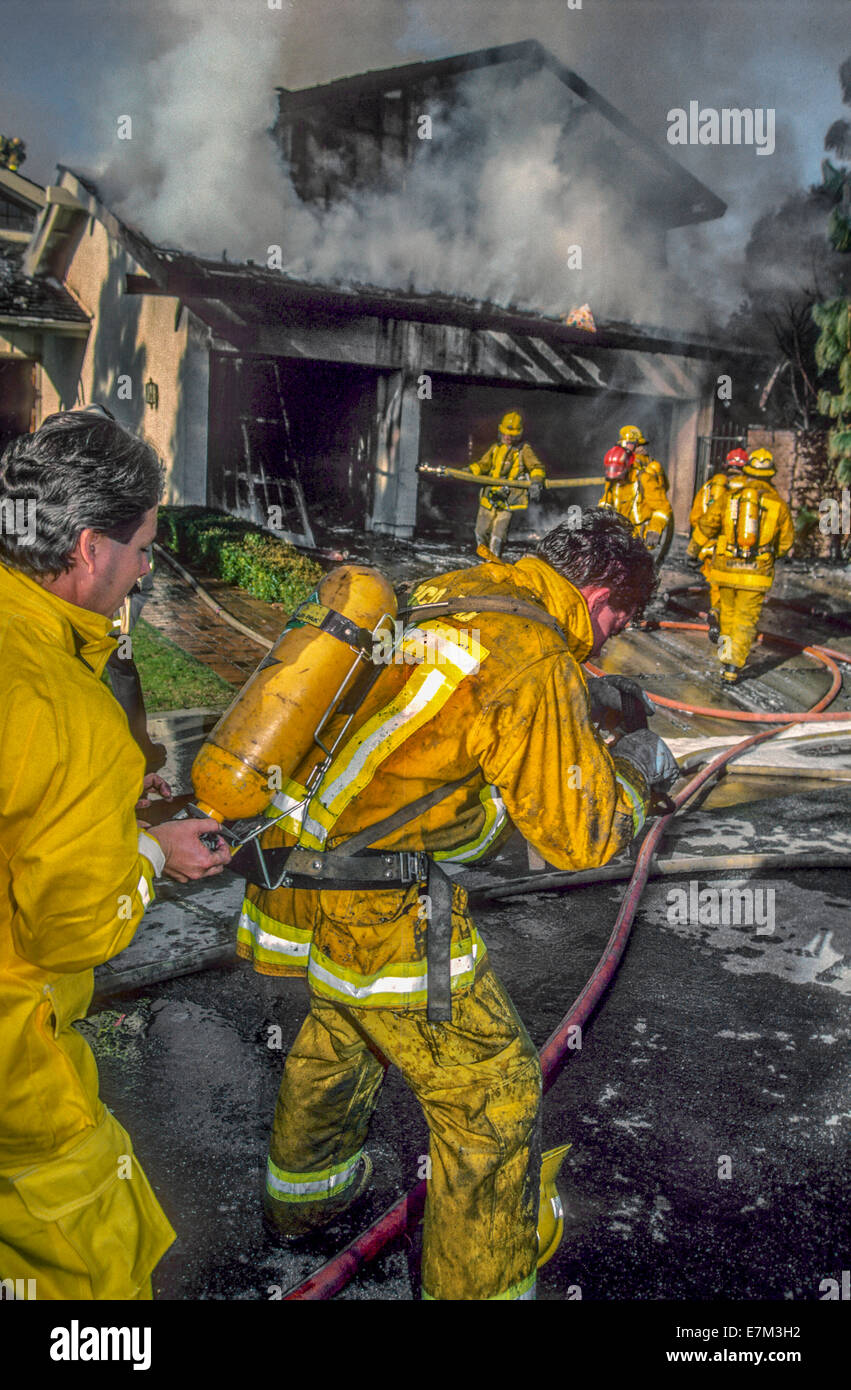 A fireman changes his colleague's air mask tank while fighting a home fire in Dana Point, CA. Stock Photo