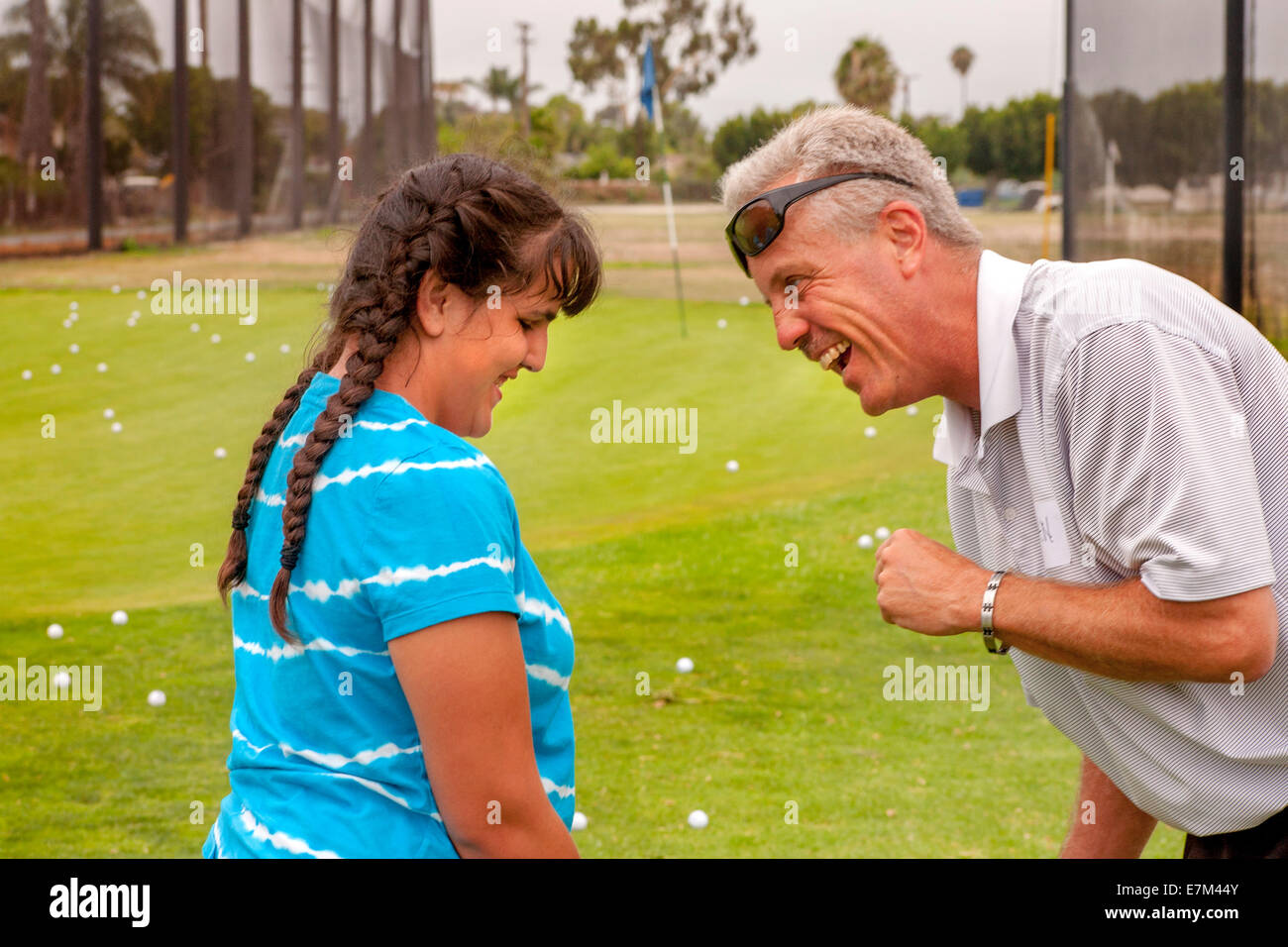A volunteer golf instructor  gives a pep talk to a blind teen girl on the chipping range at a Junior Blind Golf Clinic at a course in Seal Beach, CA. Stock Photo