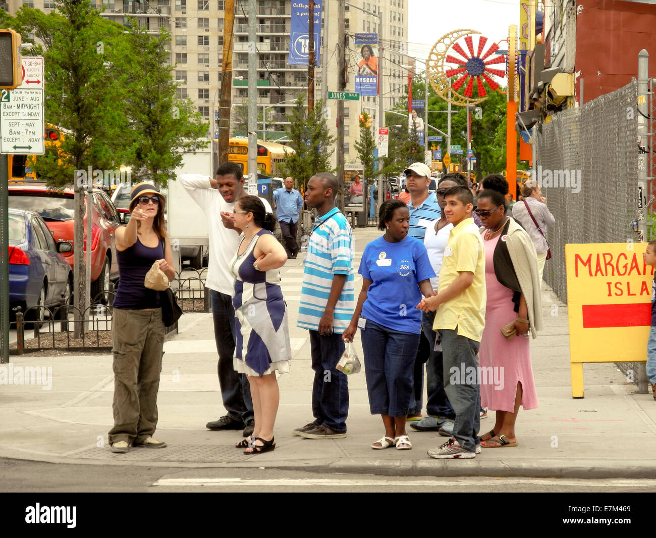 Local people wait to cross a street in Coney Island, New York City. Note, conversation, racial variety and amusement park signs. Stock Photo