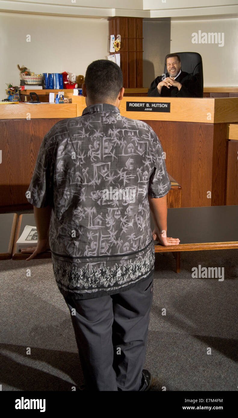 A teenage defendant  appears at a reenactment of a hearing with an African American judge Stock Photo