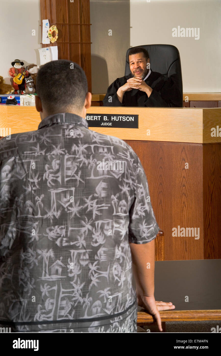 A teenage defendant appears at a reenactment of a hearing with an African American judge Stock Photo