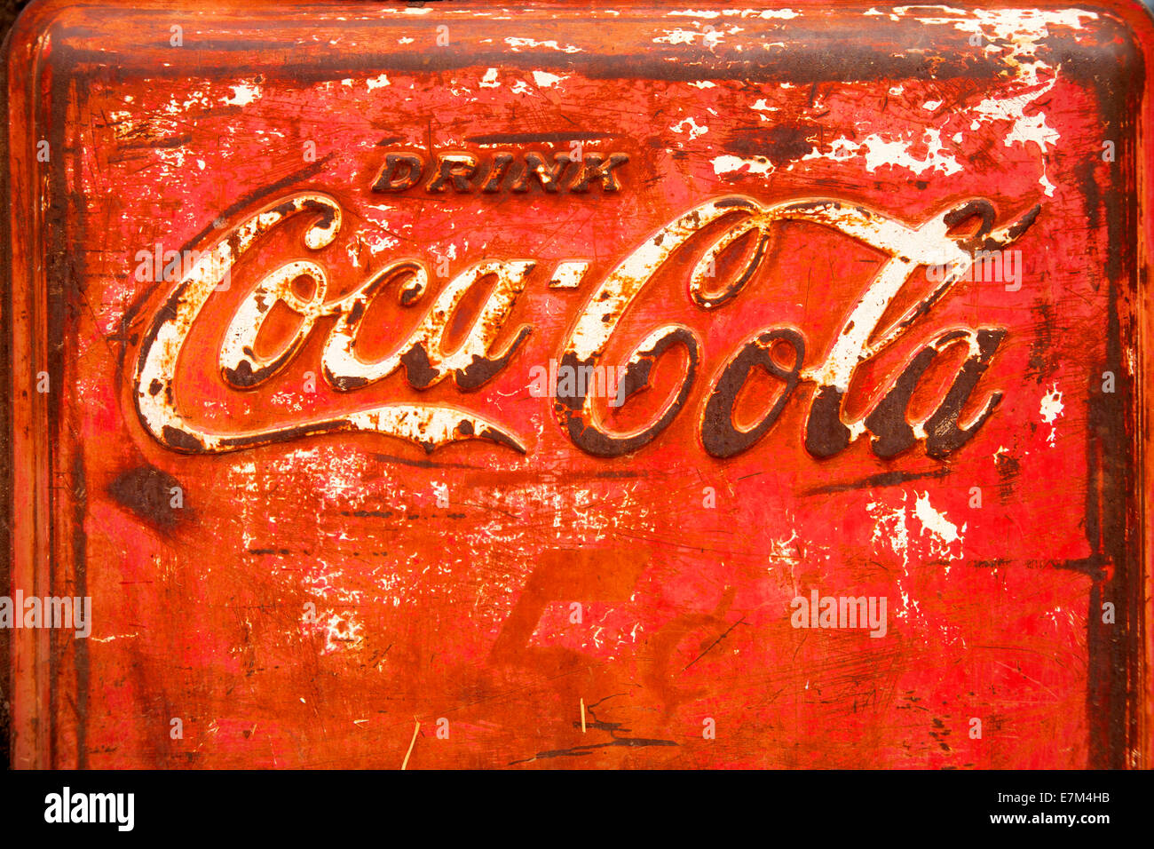 The trademark logo of Coca-Cola appears in Spencerian script on a rusted ice cooler. Stock Photo
