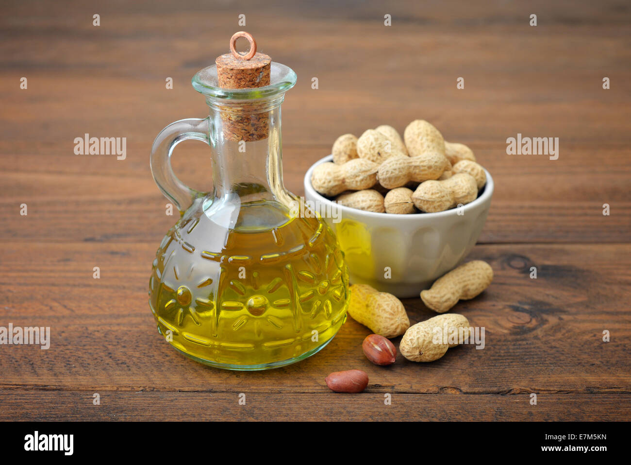 Peanut oil with raw peanuts on wooden background Stock Photo