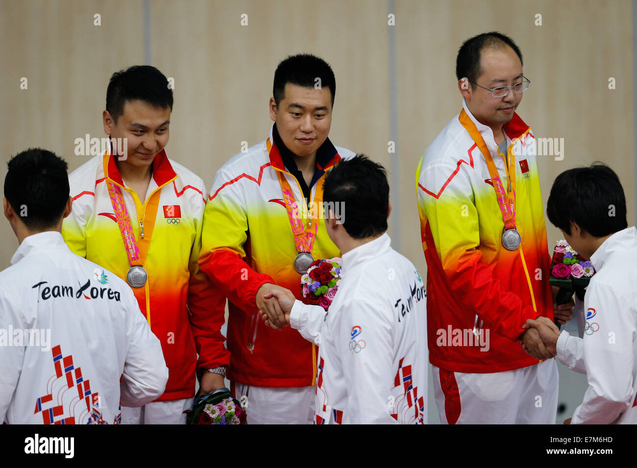 Incheon, South Korea. 21st Sep, 2014. Wang Zhiwei, Pang Wei and Pu Qifeng (L to R) of China shake hands with players of South Korean team during the awarding ceremony of the 10m Pistol men's team finals of shooting event at the 17th Asian Games in Incheon, South Korea, Sept. 21, 2014. Chinese team won the silver medal with 1,743 points. Credit:  Zhang Fan/Xinhua/Alamy Live News Stock Photo