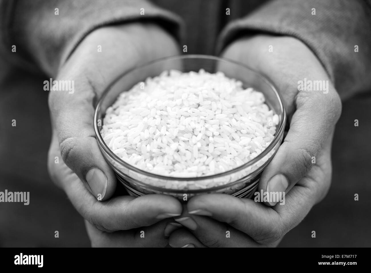 White rice in a bowl in woman's palms. Black and White image. Stock Photo