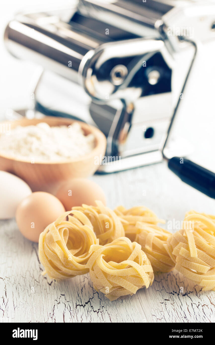 https://c8.alamy.com/comp/E7M72K/tagliatelleeggs-and-pasta-machine-on-old-table-E7M72K.jpg