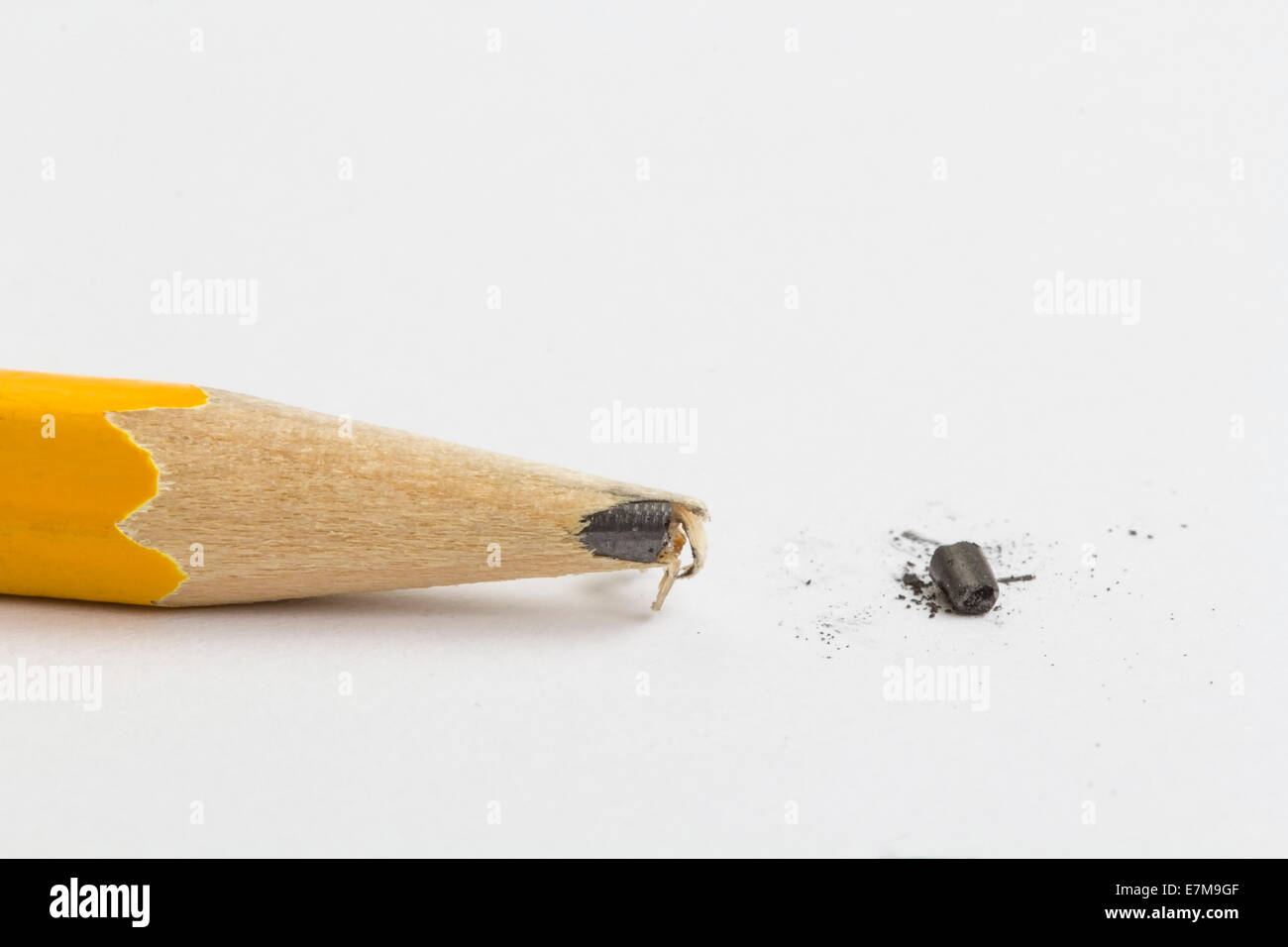 Yellow pencil over a blank sheet of paper with a broken tip. Focus on the tip of the pencil. Stock Photo