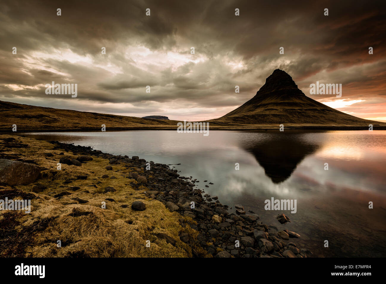 The Kirkjufell mountain reflected in the water of Grundarfjordur bay at sunrise, Snaefellsnes Peninsula, in western Iceland. Stock Photo