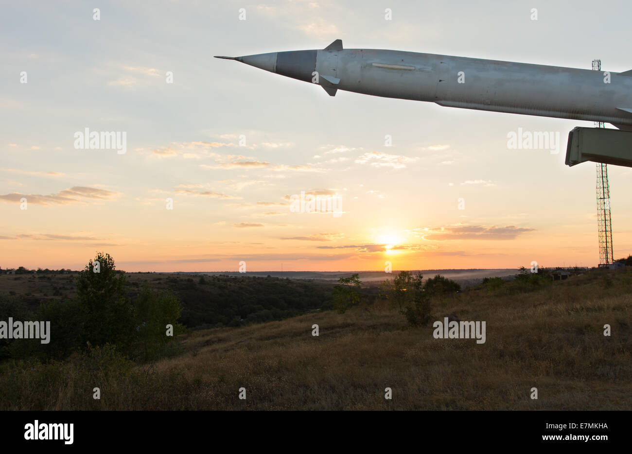 Missile with a warhead on a launcher at dusk with the sun setting in a golden glow on the horizon Stock Photo