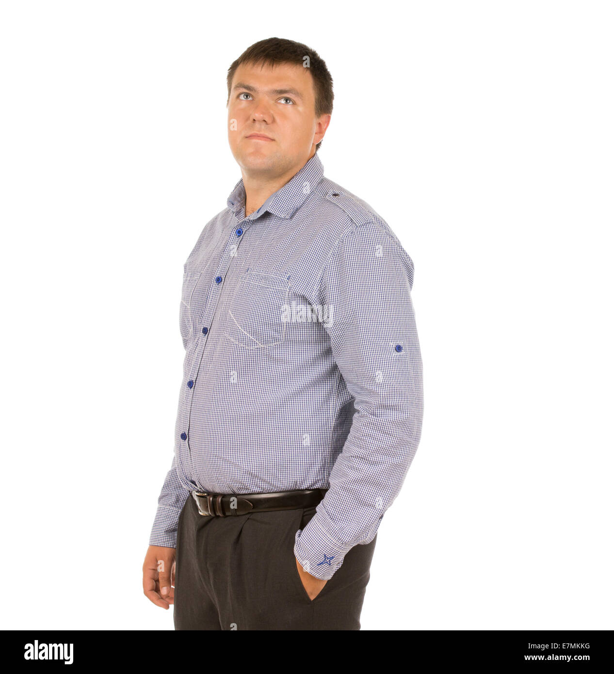 Thoughtful serious young man standing in a relaxed pose with his hand ...