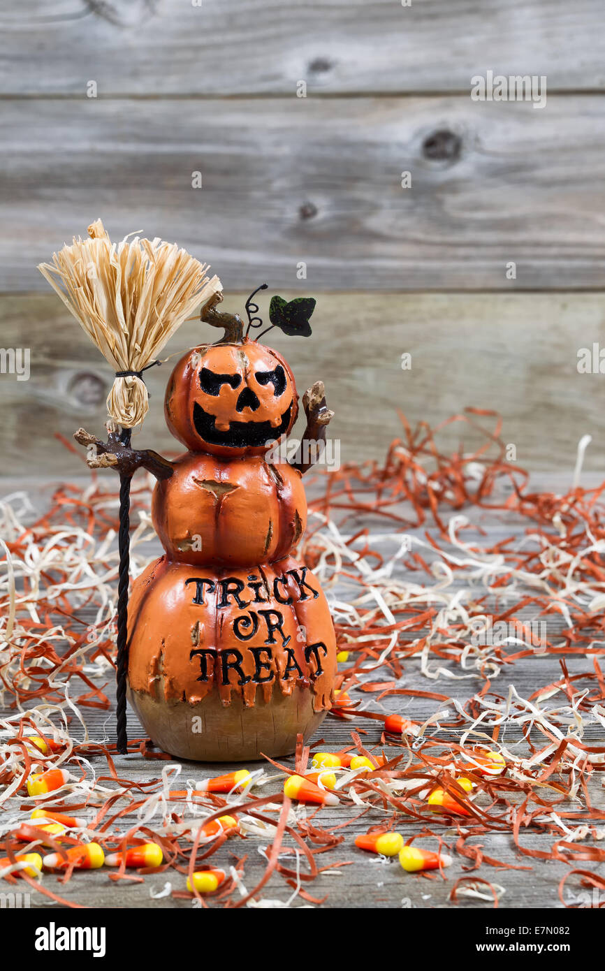 Vertical image of a scary orange pumpkin figure holding straw broom placed on rustic wooden boards Stock Photo