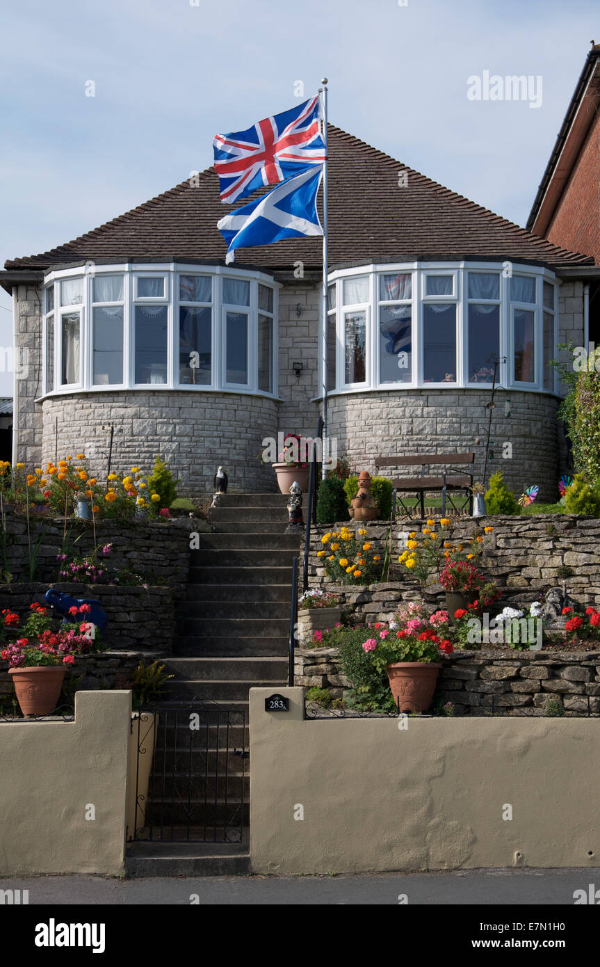 United Kingdom flags. The Union Jack and Scottish Saltire fly above a bungalow in England during the 2014 Scottish independence referendum campaign. Stock Photo