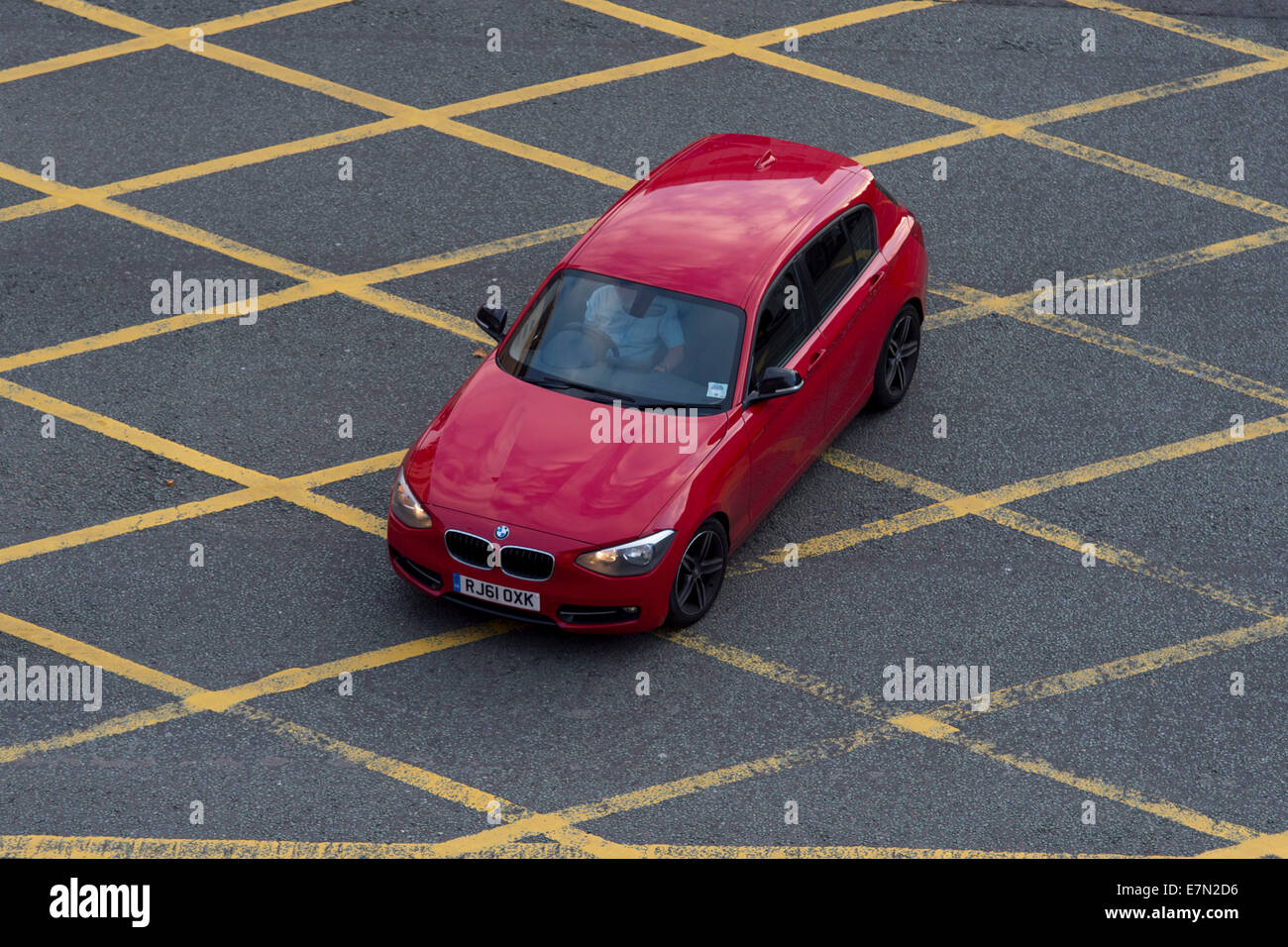 A red car in a yellow box junction. Stock Photo