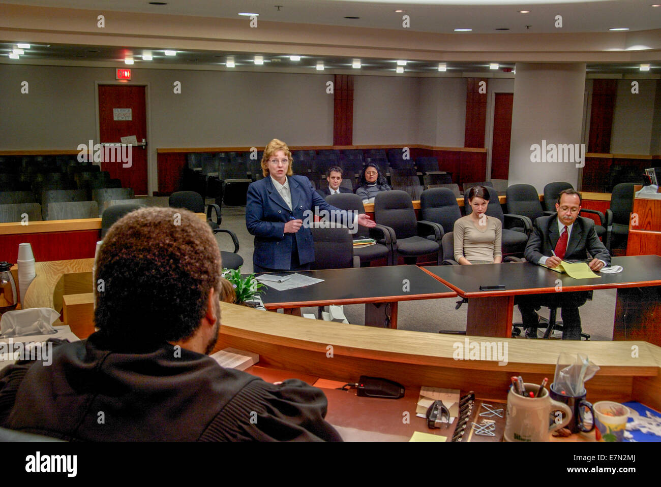 A lawyer advocates for her teenage Hispanic client in juvenile court in Orange, CA. Note parents in background and African American judge. Stock Photo