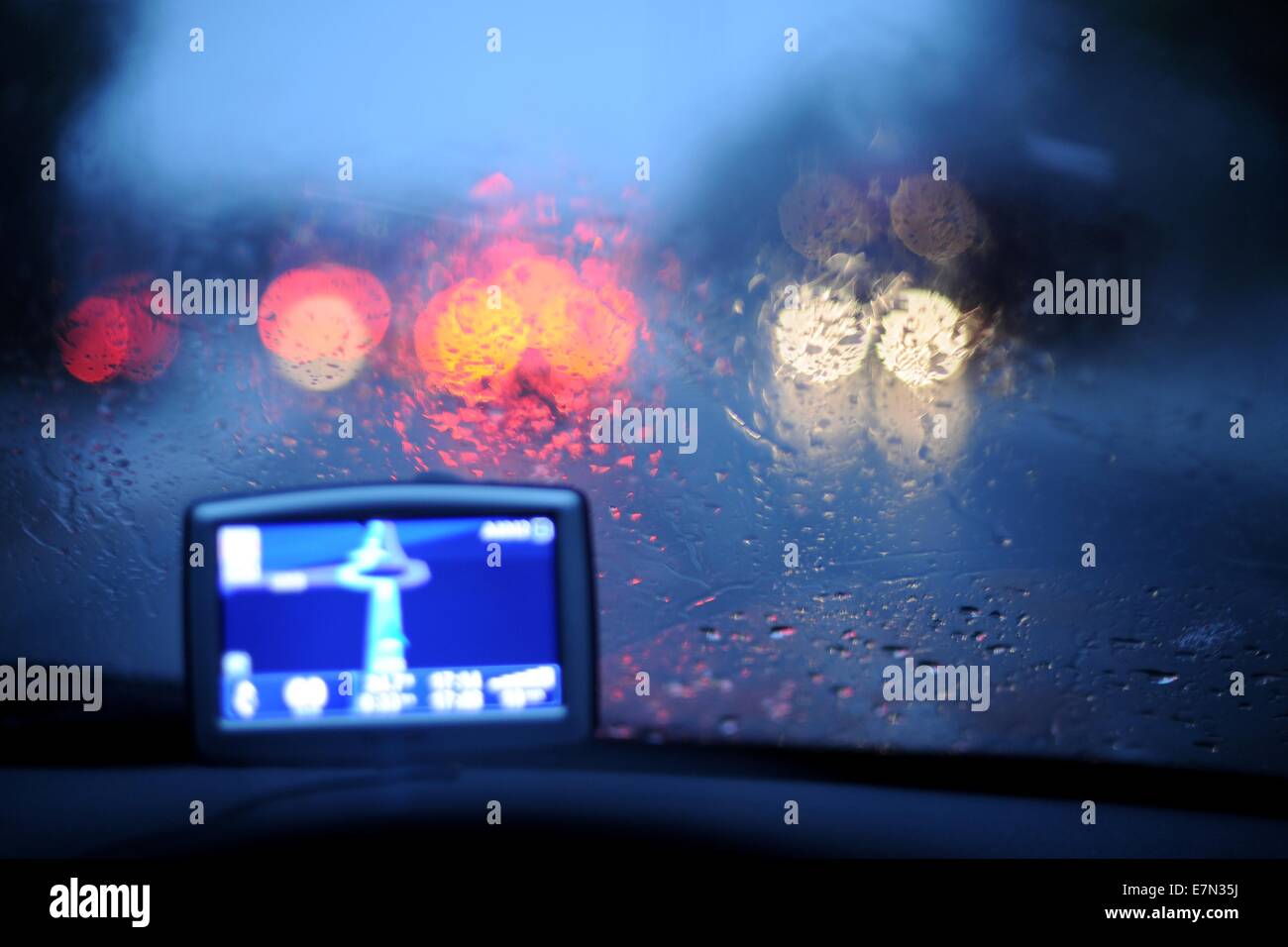 A satellite navigational (sat nav) fitted in a car driving at night in the rain. Stock Photo