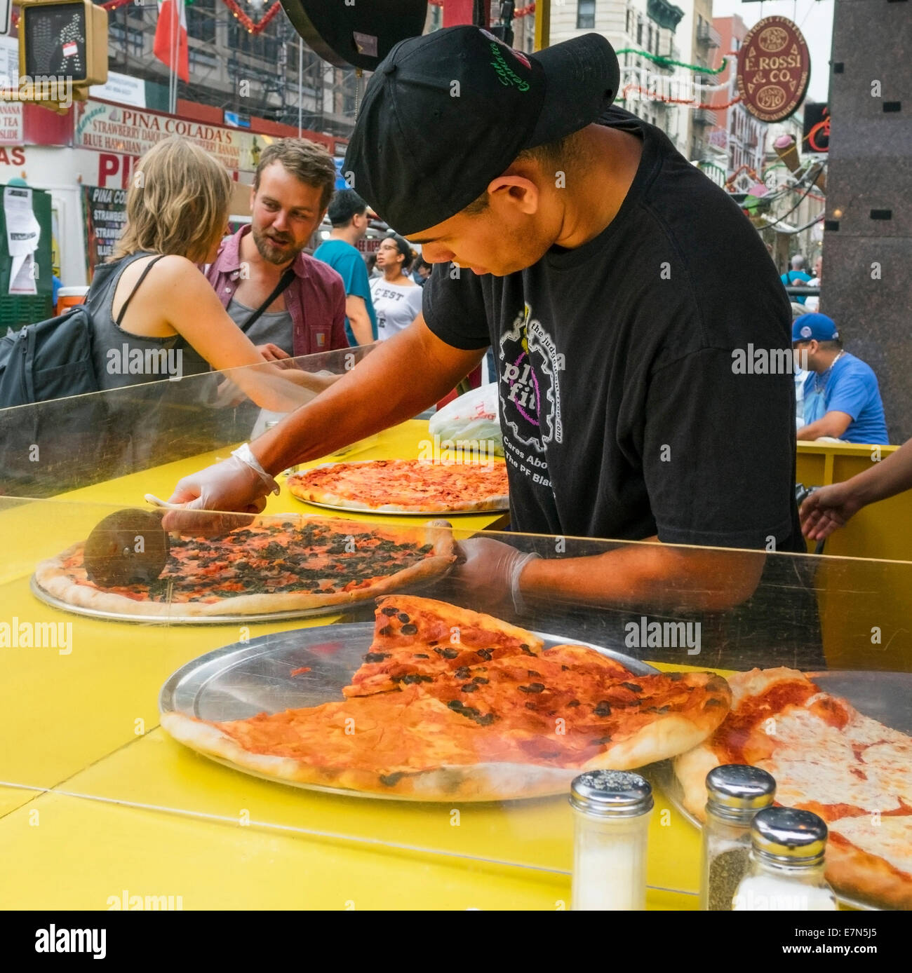 A man cutting a pizza into slices in Little Italy in New York City during the San Gennaro Feast Stock Photo