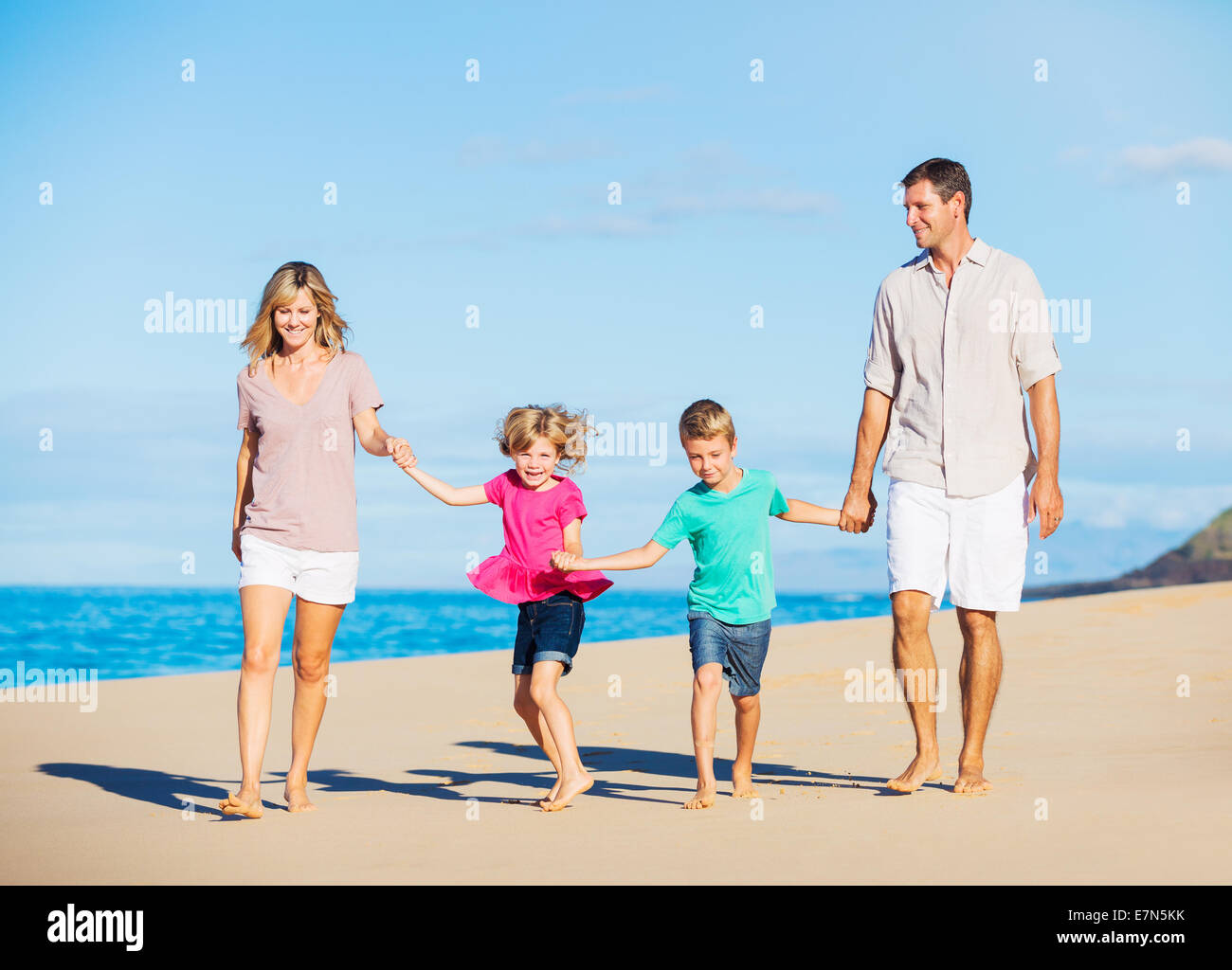 Happy Healthy Family of Four having Fun Walking on Tropical Beach Stock Photo