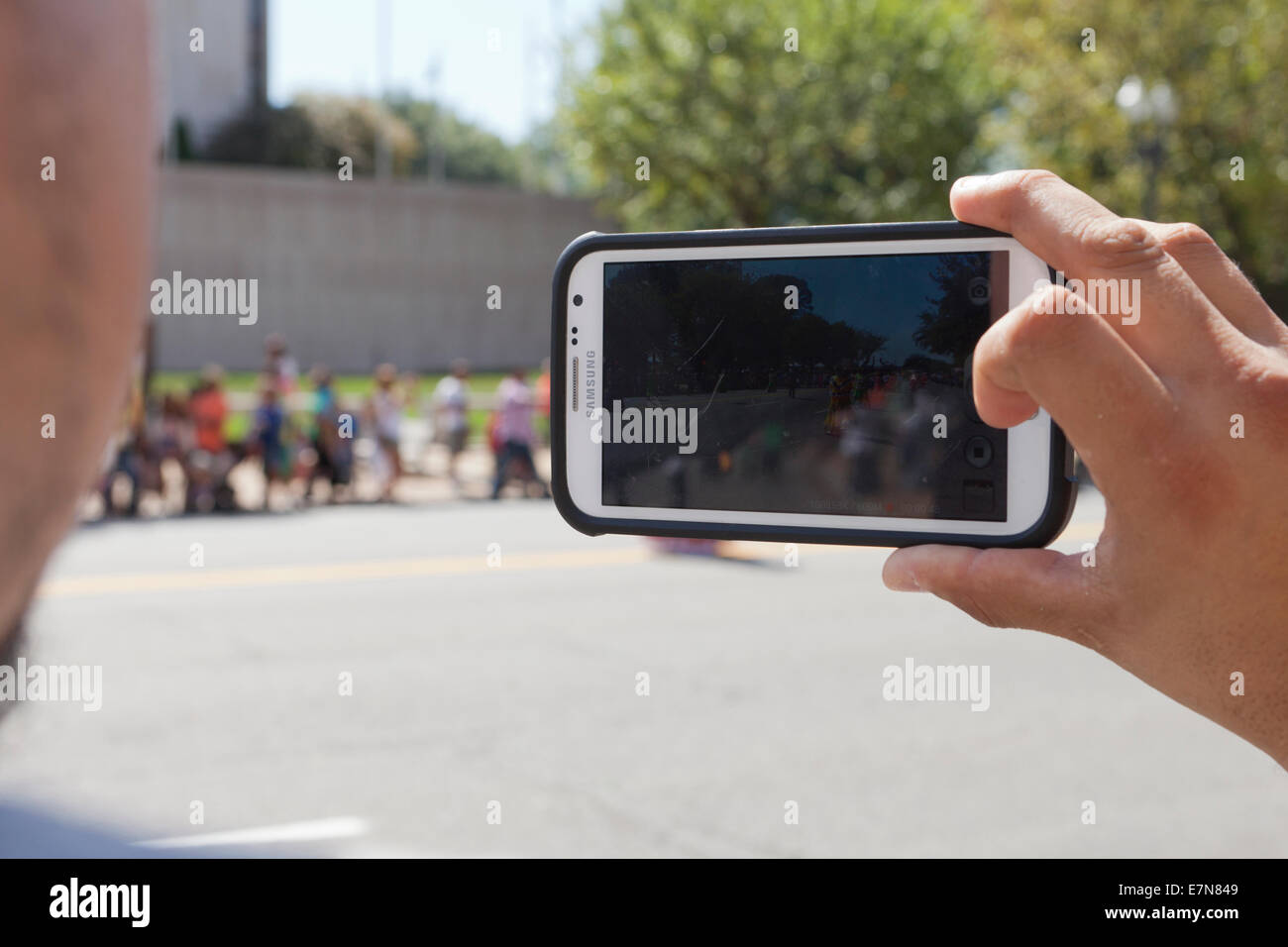 Man capturing video of event at an outdoor festival with smart phone - USA Stock Photo