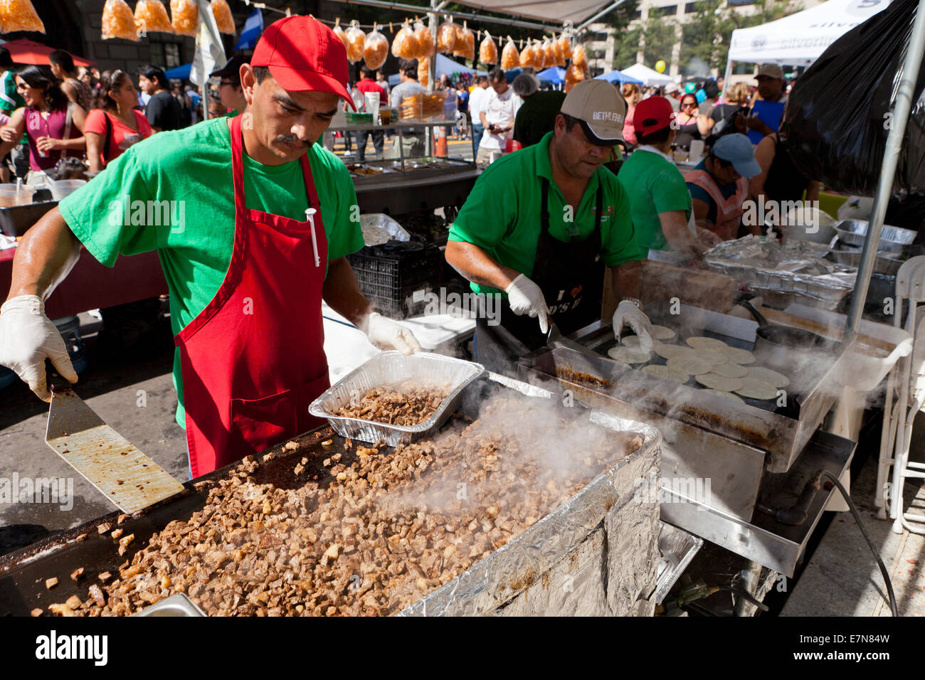 Man grilling chopped pork meat on large griddle at an outdoor food festival - USA Stock Photo