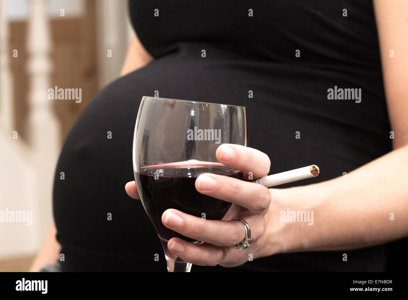 Pregnant woman holding a cigarette and glass of wine Stock Photo