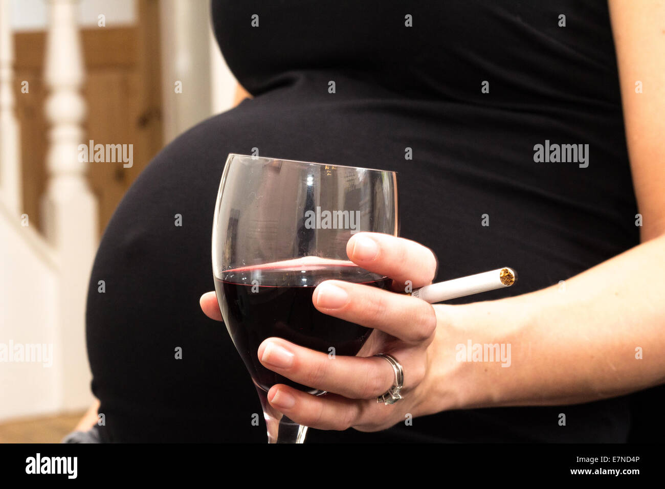 Pregnant woman holding a cigarette and glass of wine Stock Photo