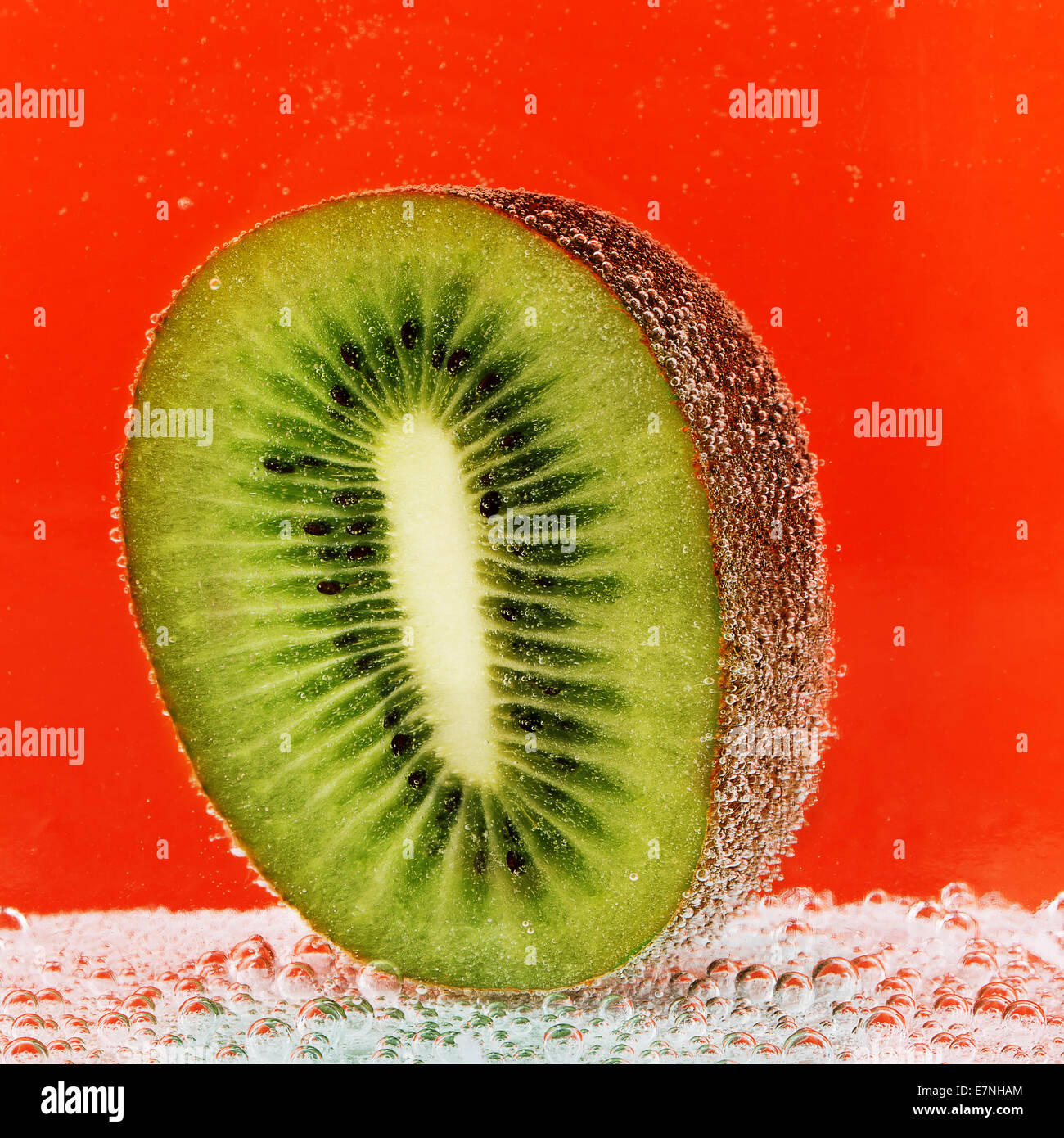 half of kiwi with bubbles in soda water Stock Photo