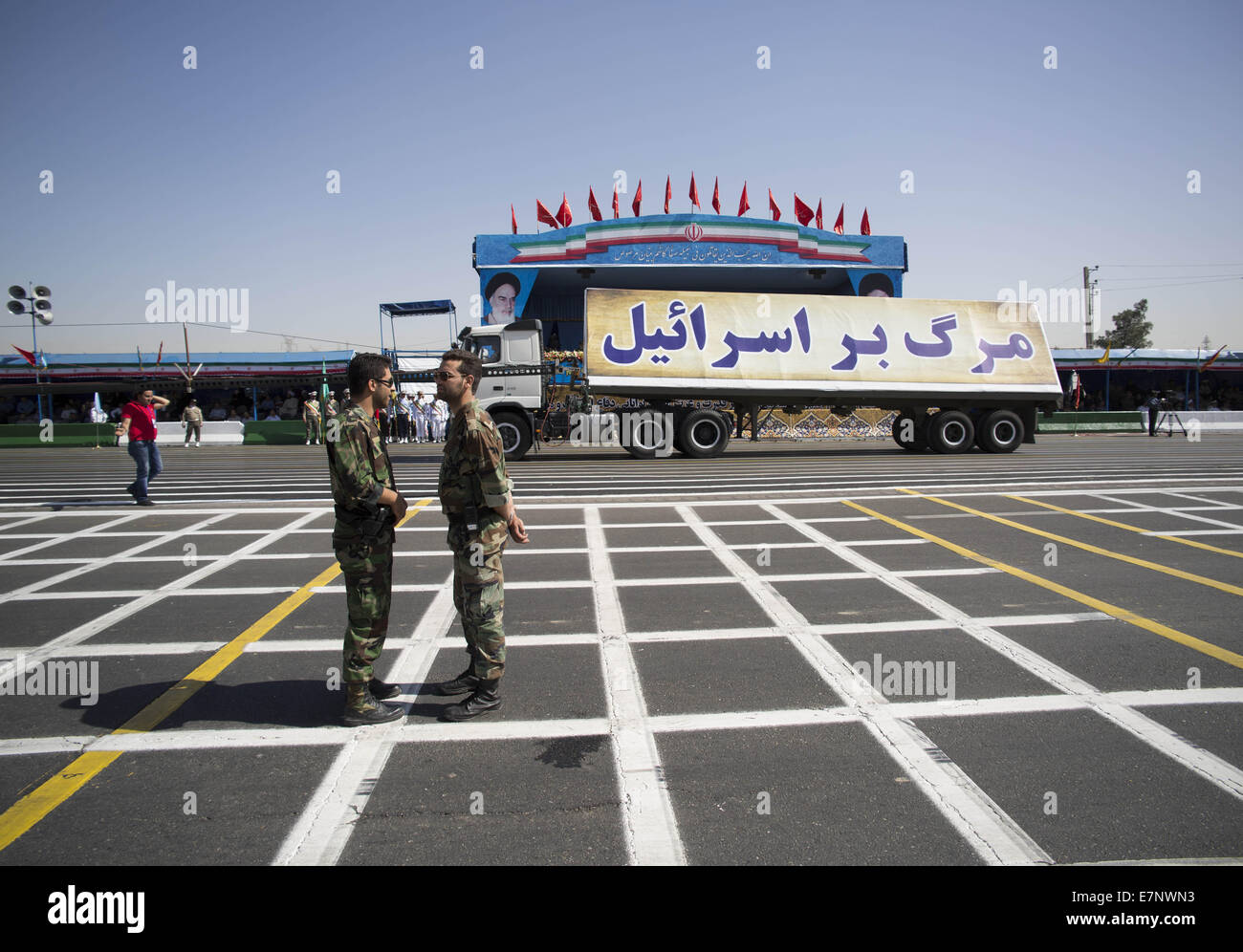 Tehran, Iran. 22nd Sep, 2014. September 22, 2014 - Tehran, Iran - Two members of Iran's Revolutionary guard talk to each other as a vehicle carrying an anti-Israel banner during a military parade to commemorate the anniversary of the Iran-Iraq war (1980-88) in Tehran. Banner said, Down with Israel. Morteza Nikoubazl/ZUMAPRESS Credit:  Morteza Nikoubazl/ZUMA Wire/Alamy Live News Stock Photo