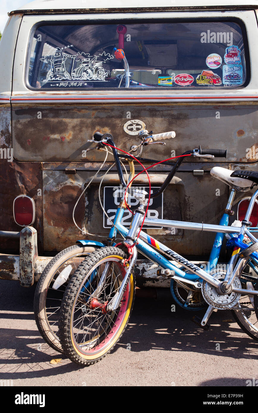 Childrens bicycles next to the rear of a rusty VW Rat style Volkswagen camper van at a VW show. England Stock Photo