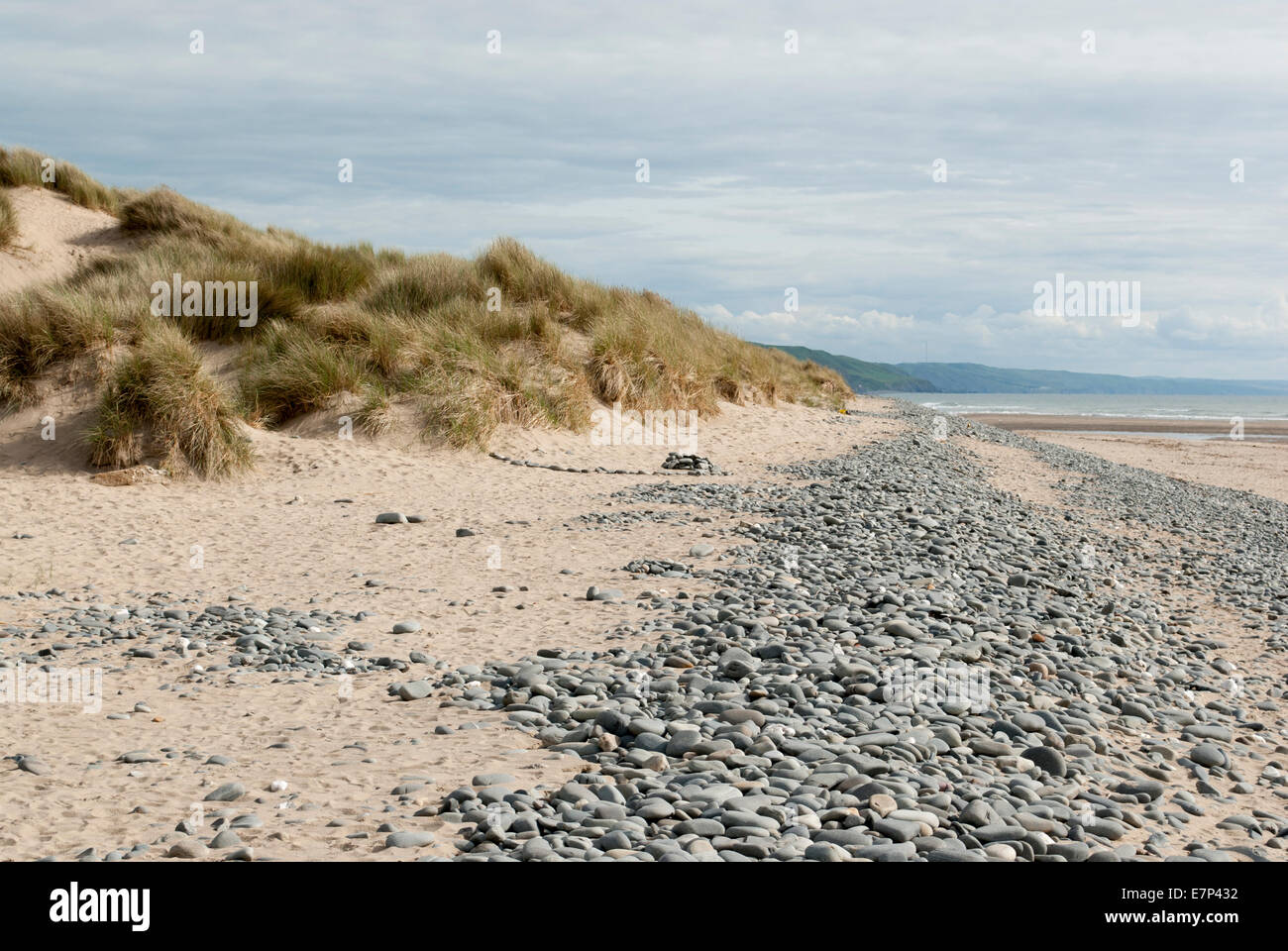 low down shot of beach with pebbles and grassy dunes in Ynyslas, Wales, UK Stock Photo