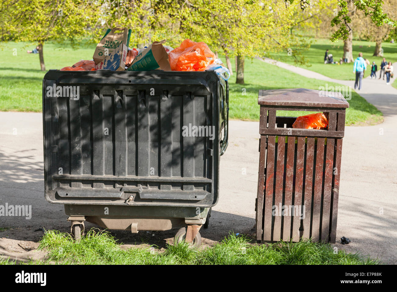 Large wheelie bin next to a litter bin, both bins full with rubbish at a park in London, England