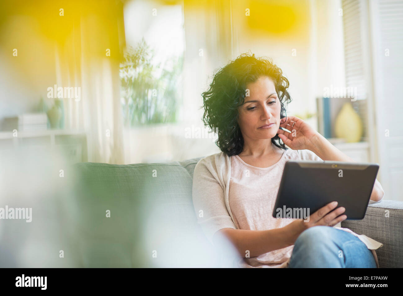 Woman using digital tablet on sofa Stock Photo - Alamy