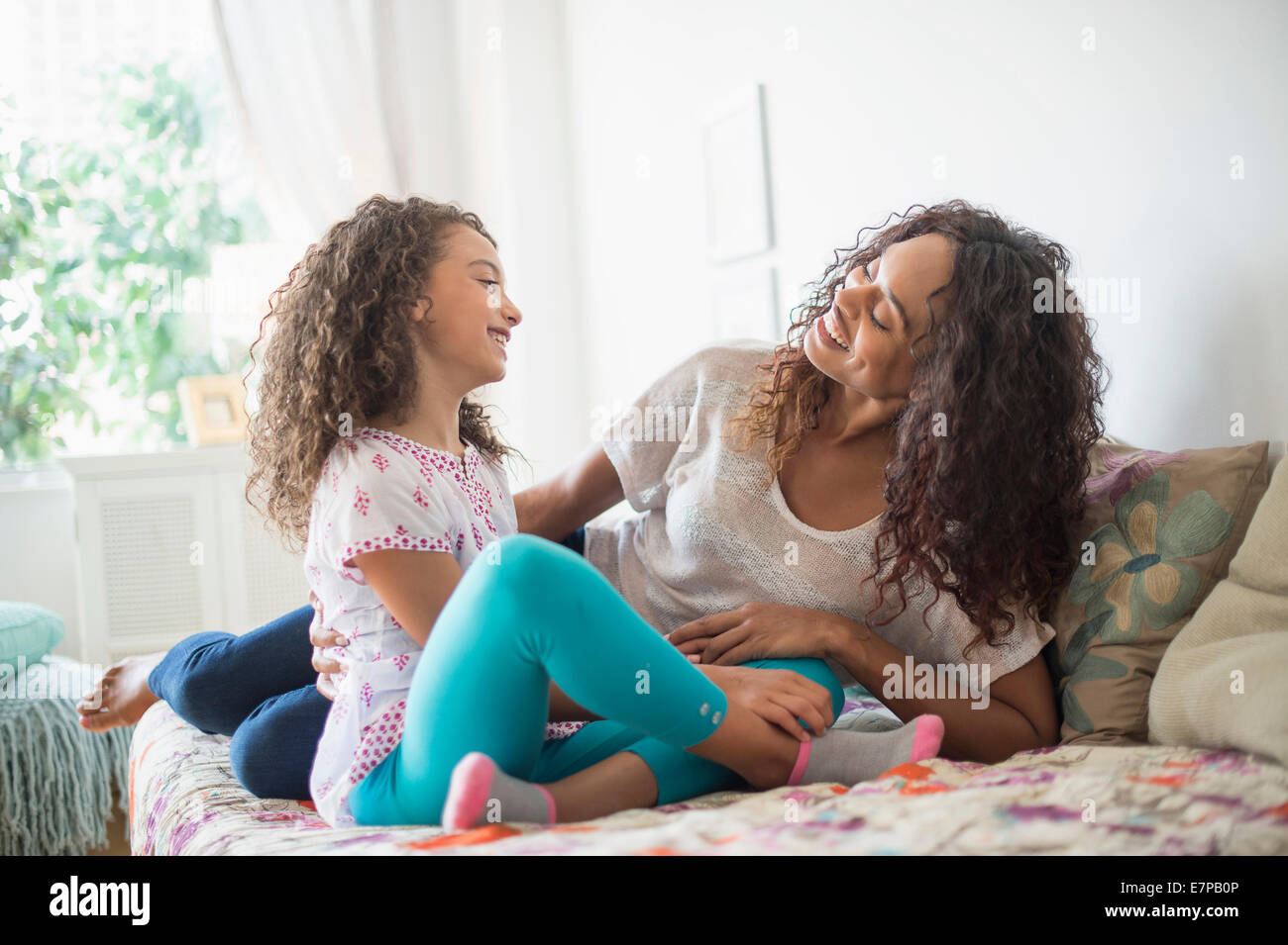 Mother and daughter (8-9) sitting on bed Stock Photo