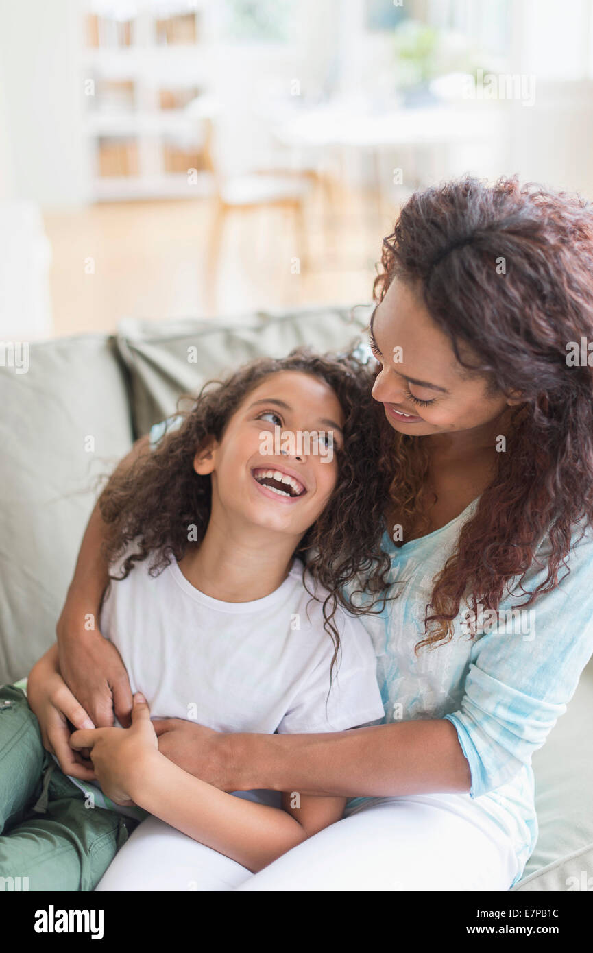 Mother embracing daughter (8-9) in living room Stock Photo