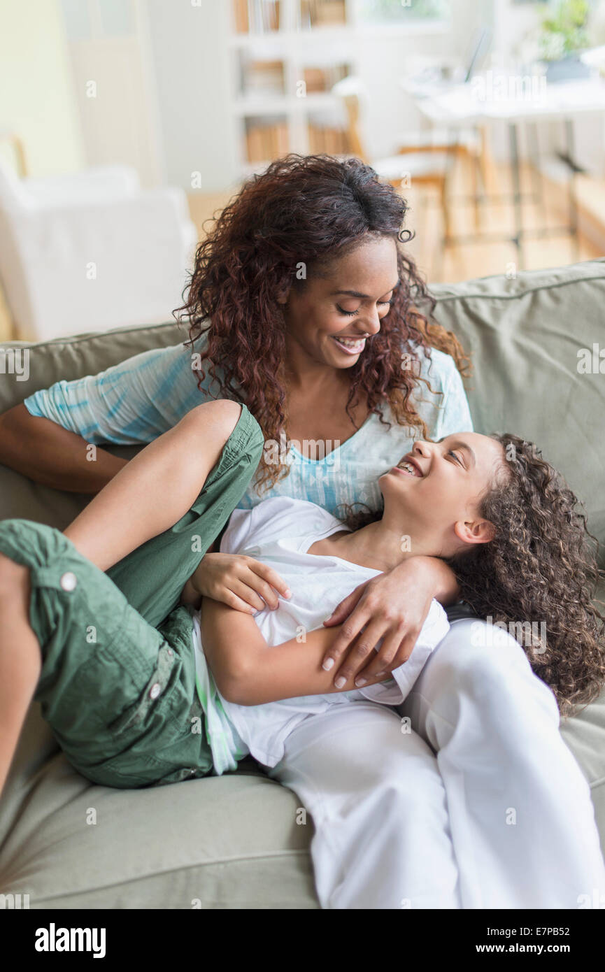 Mother tickling daughter (8-9) on sofa Stock Photo