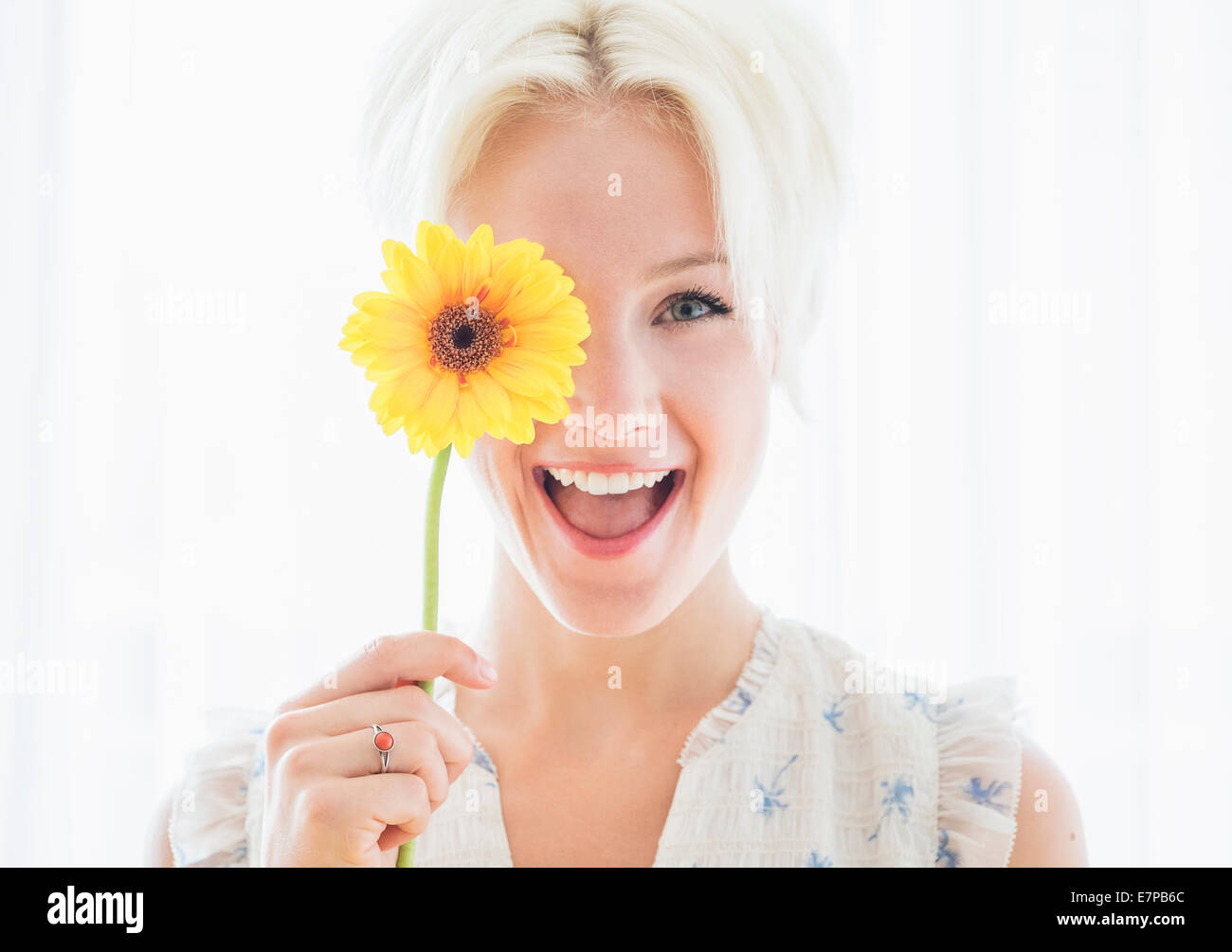 Portrait of blonde woman holding yellow flower Stock Photo