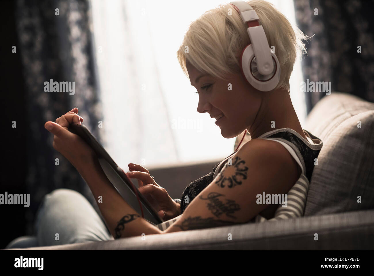 Woman sitting on sofa using digital tablet Stock Photo - Alamy