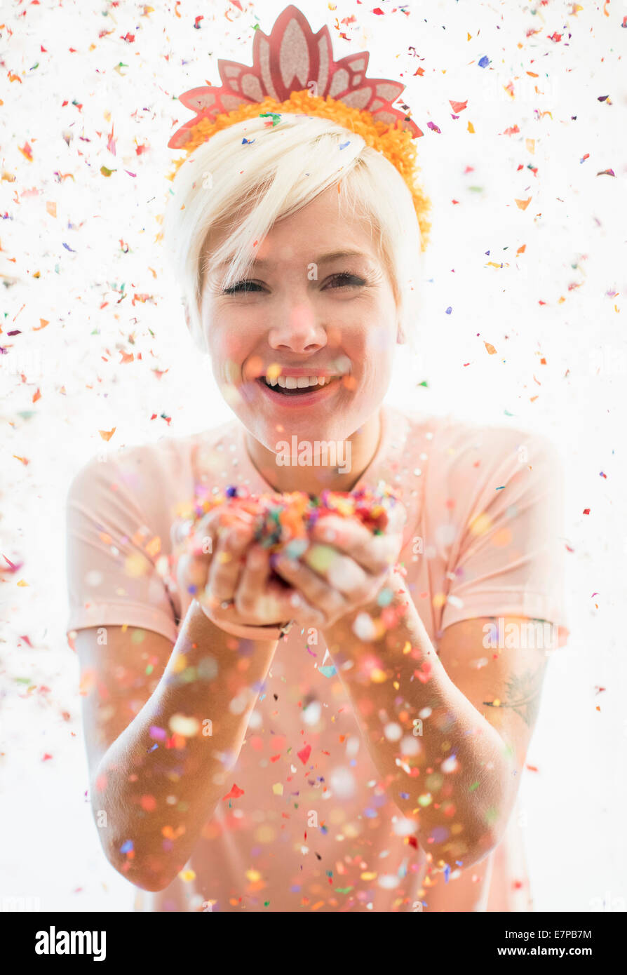 Woman wearing tiara blowing confetti Stock Photo