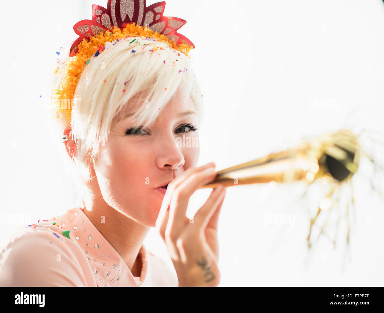 Woman wearing tiara blowing party horn blower Stock Photo