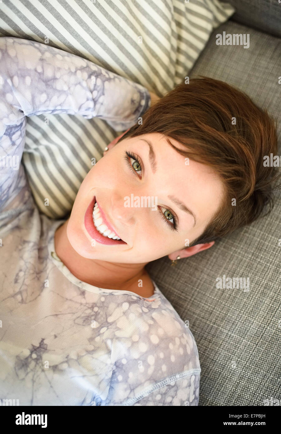 Portrait of smiling woman lying on sofa Stock Photo