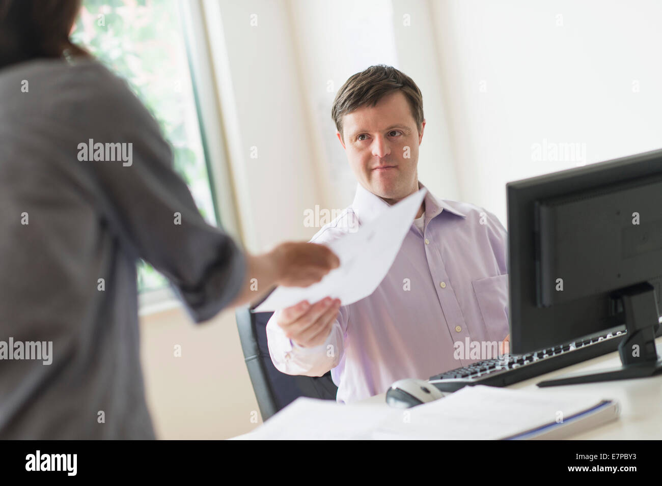 Man with down syndrome working in office Stock Photo