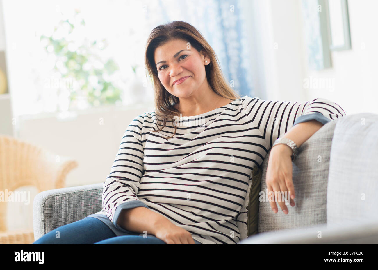 Portrait of happy woman sitting on sofa Stock Photo - Alamy