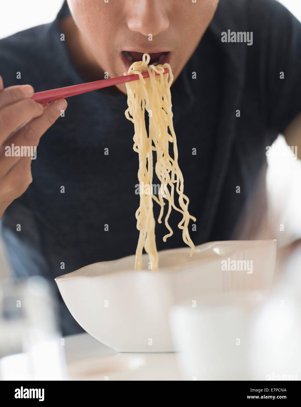 Man eating noodles with chopsticks Stock Photo