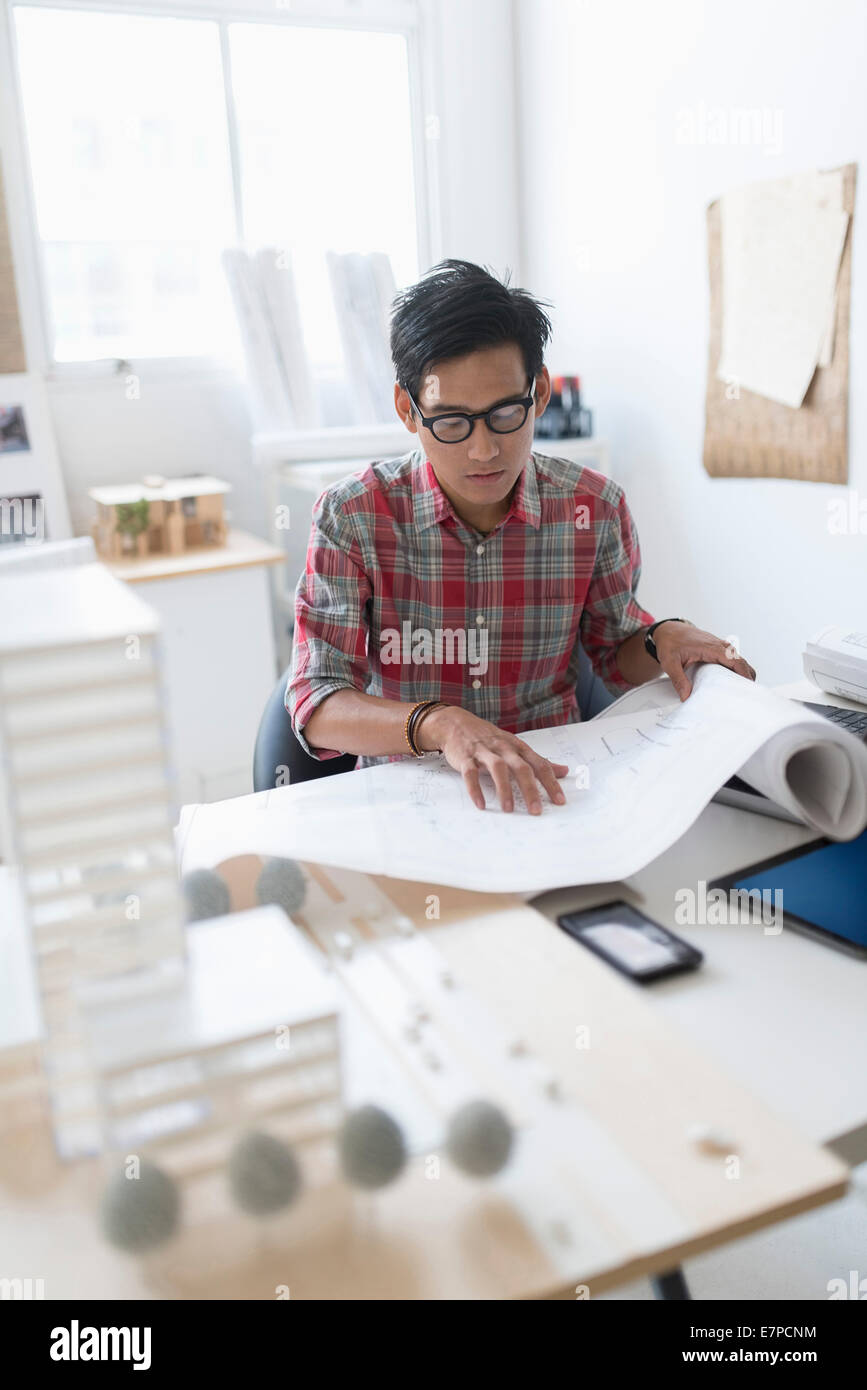 Architect looking at blueprints in office Stock Photo