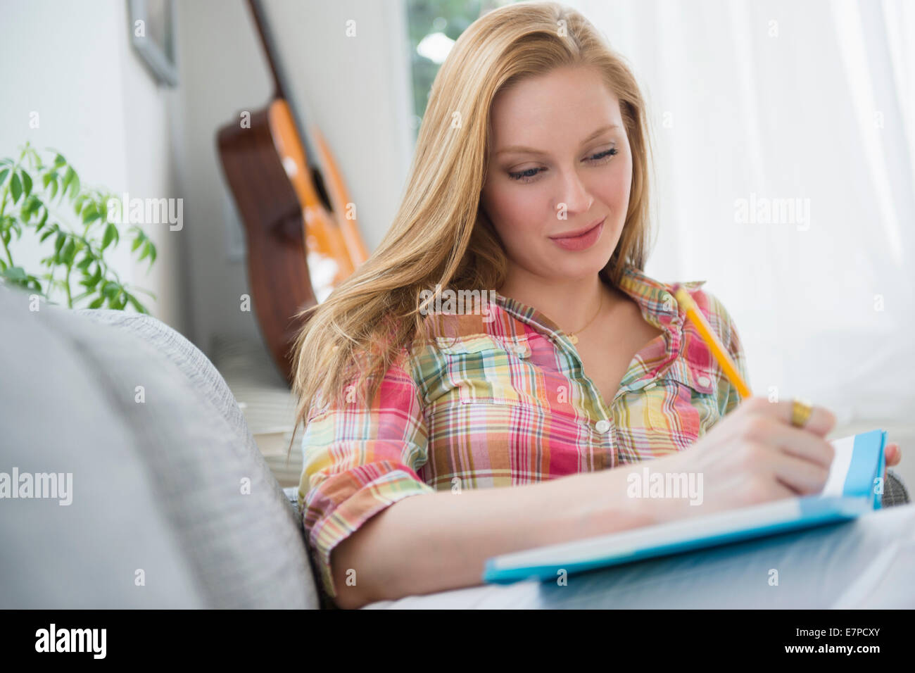 Portrait of young woman writing journal on sofa Stock Photo
