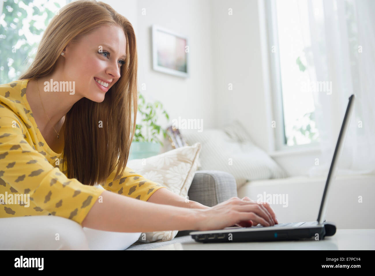 Young woman using laptop in living room Stock Photo